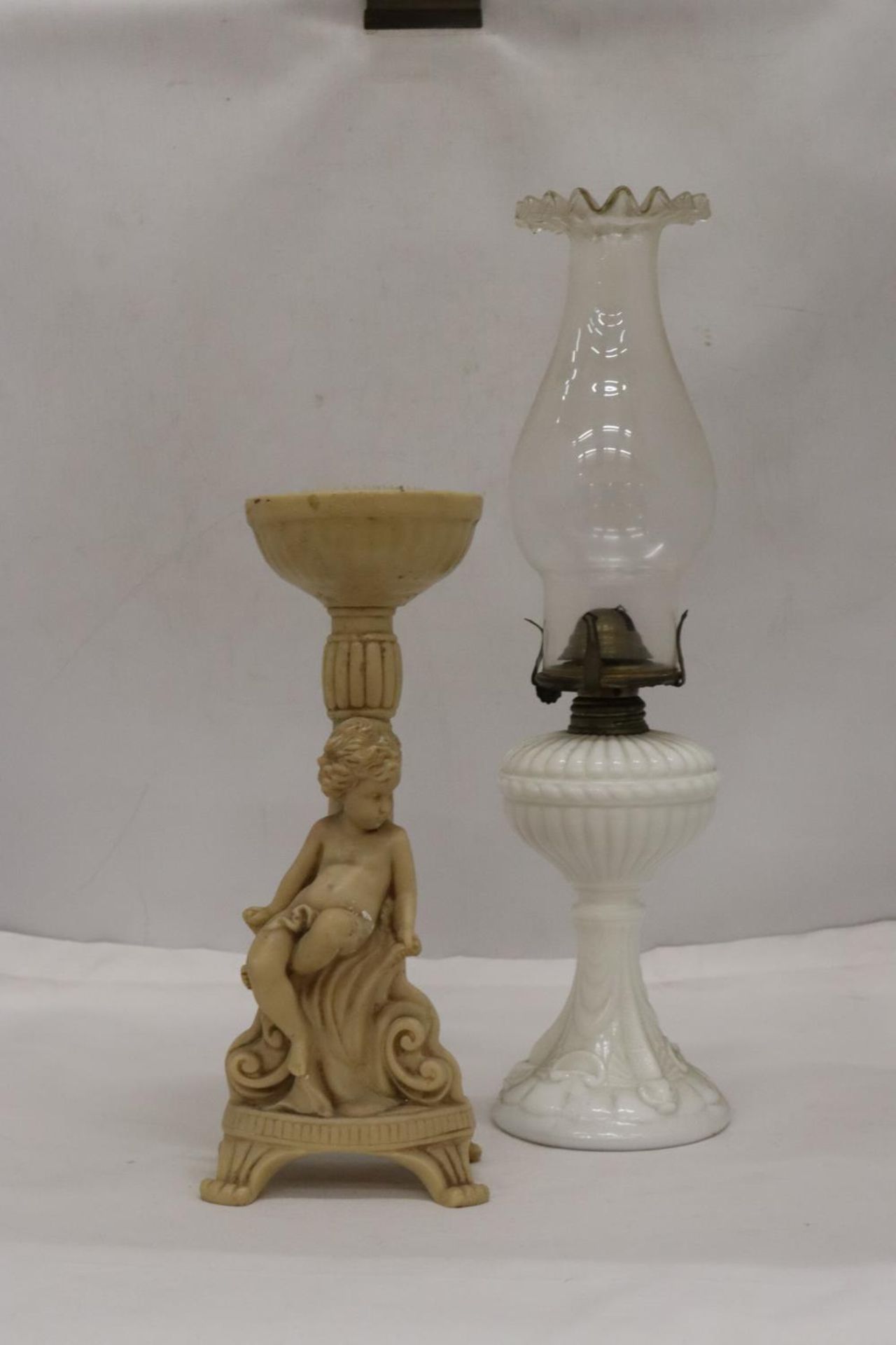 A WHITE BASED GLASS FLUTED SHADE OIL LAMP AND A CHERUB DESIGN FLOWER ARRANGIMG STAND