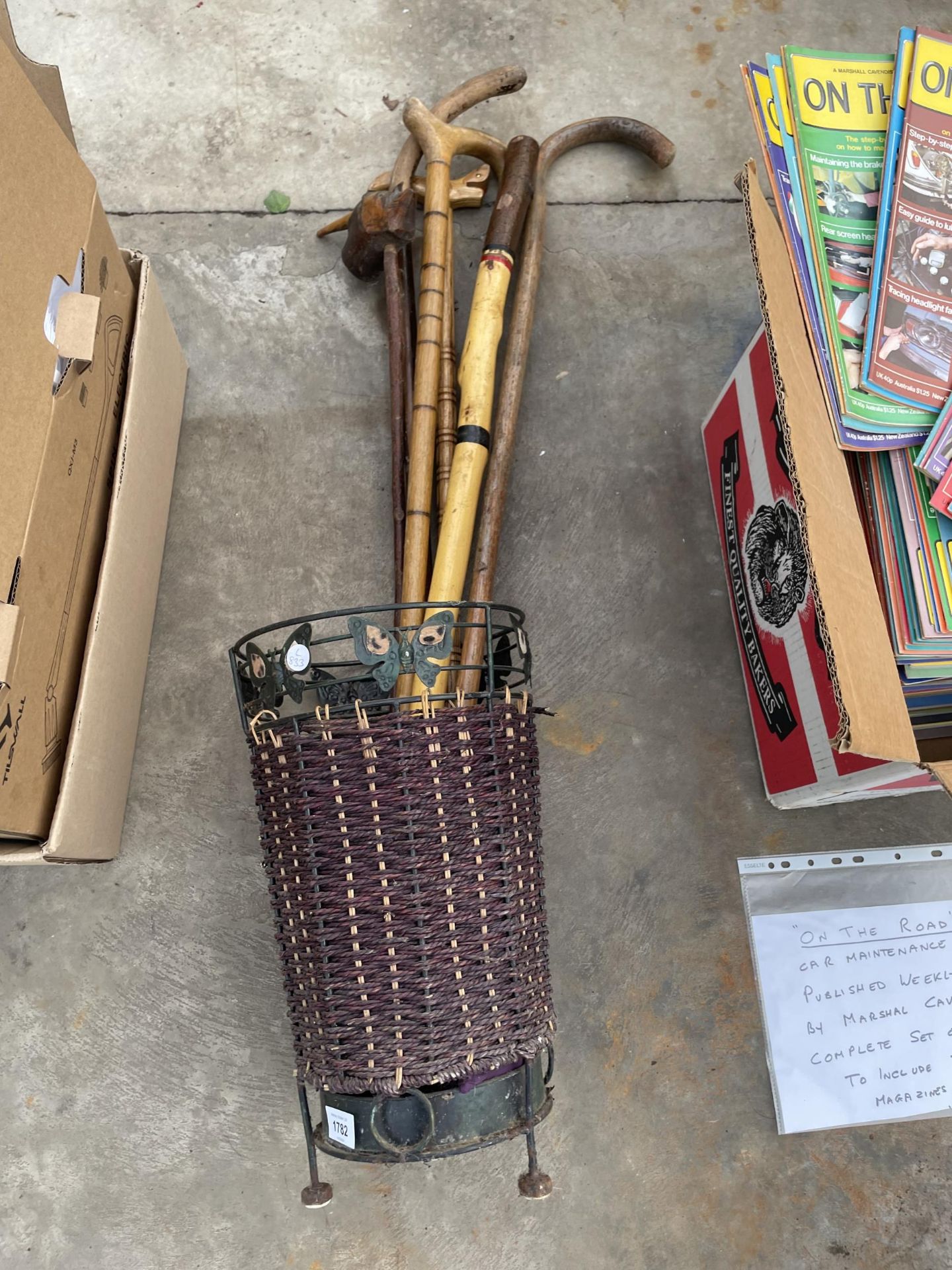 A WICKER STICK STAND WITH AN ASSORTMENT OF WALKING STICKS