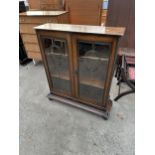 AN EARLY 20TH CENTURY OAK TWO DOOR GLAZED BOOKCASE WITH BEVELLED GLASS OVALS 33" WIDE