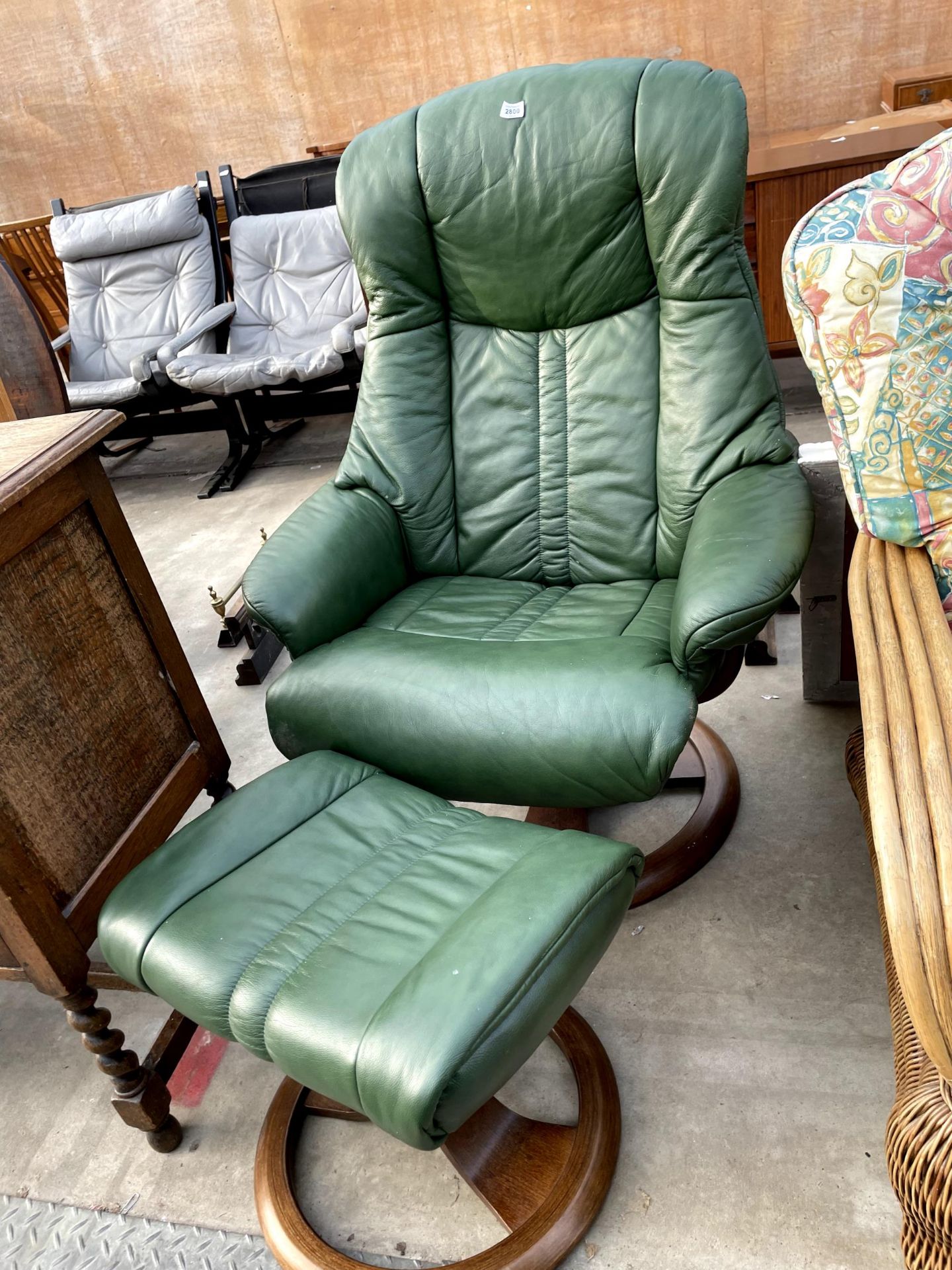 A GREEN LEATHER SWIVEL RECLINER AND STOOL