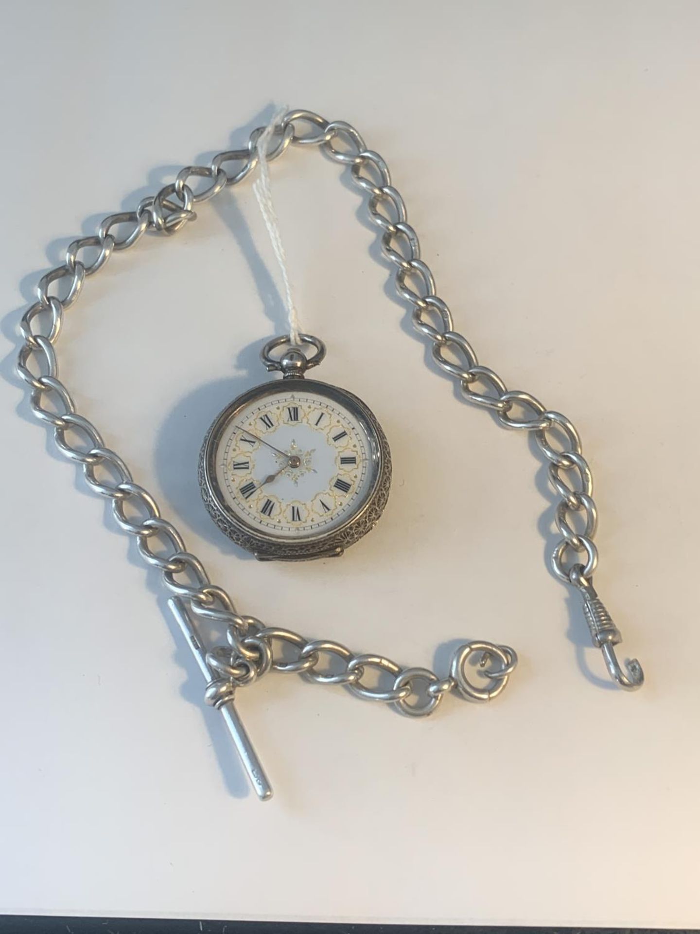 A MARKED 935 SILVER LADIES POCKET WATCH WITH DECORATIVE FACE AND CASE WITH A MARKED T BAR CHAIN