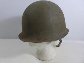 A GREEN PAINTED METAL MILITARY HELMET AND LINING