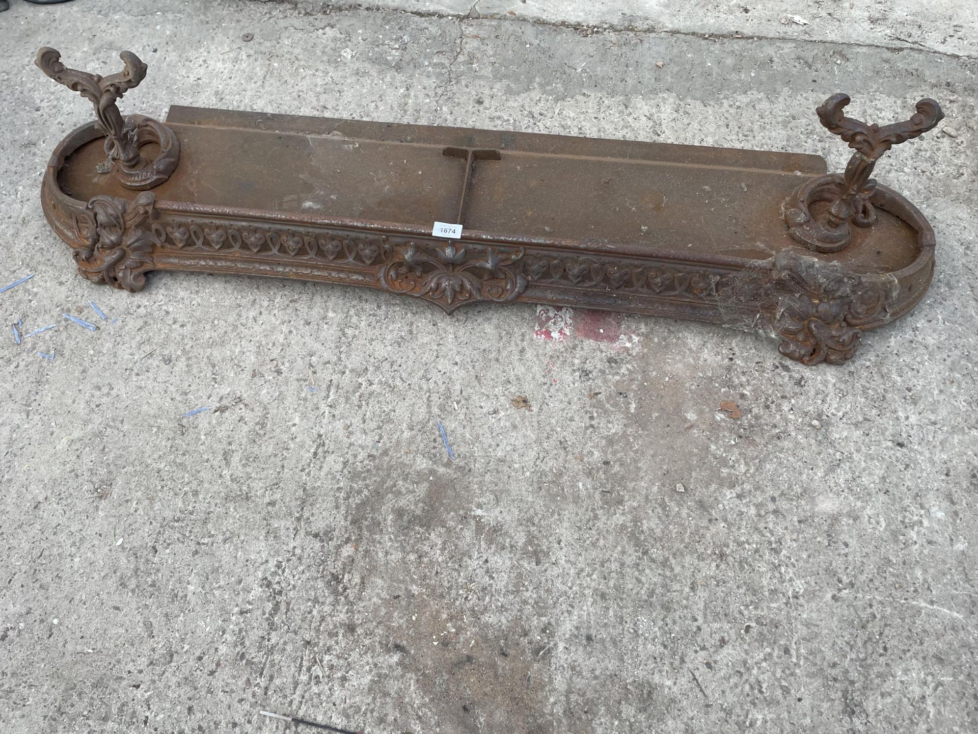 A VINTAGE HEAVILY DECORATED CAST IRON FIRE FENDER
