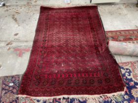 A SMALL RED PATTERNED FRINGED RUG