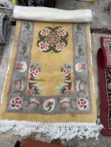 A SMALL YELLOW PATTERNED FRINGED RUG