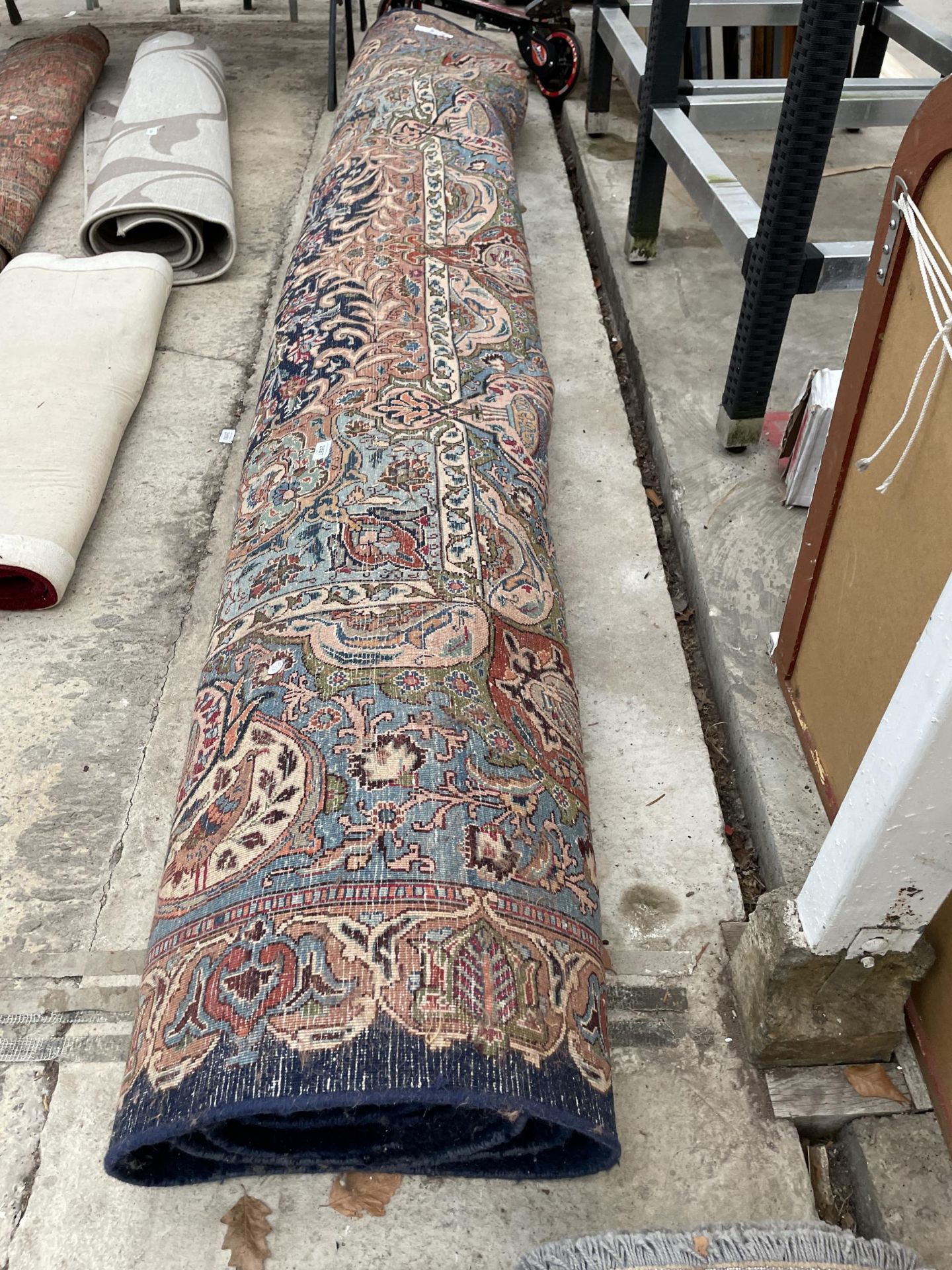 A LARGE BLUE PATTERNED FRINGED RUG