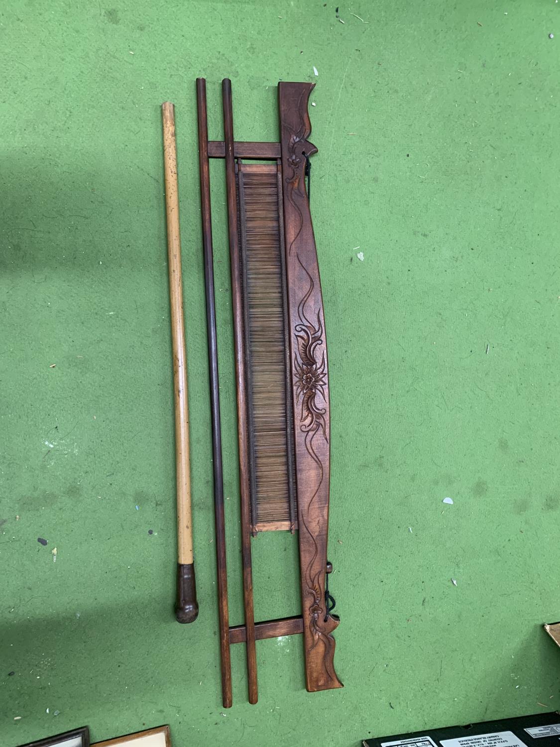 A VINTAGE WOODEN WEAVING IMPLEMENT PLUS A WALKING STICK WITH A WEIGHTED TOP