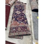 A LARGE BLUE AND RED PATTERNED FRINGED RUG