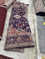 A LARGE BLUE AND RED PATTERNED FRINGED RUG