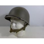 A GREEN PAINTED METAL MILITARY HELMET AND LINING