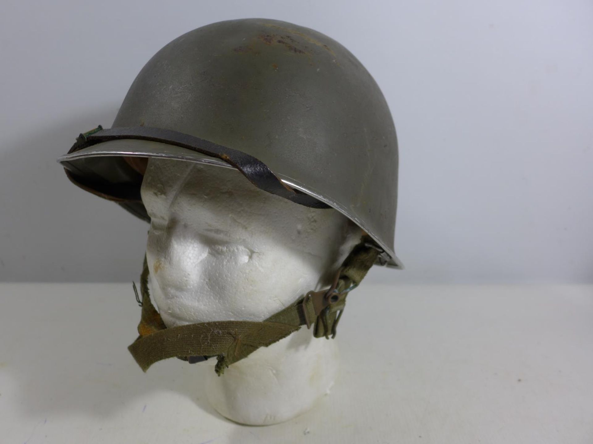 A GREEN PAINTED METAL MILITARY HELMET AND LINING