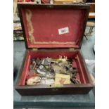 A VINTAGE WOODEN BOX CONTAINING A QUANTITY OF COLLECTABLE ITEMS TO INCLUDE A SKULL, PENS, COSTUME