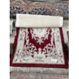 A SMALL RED PATTERNED FRINGED RUG