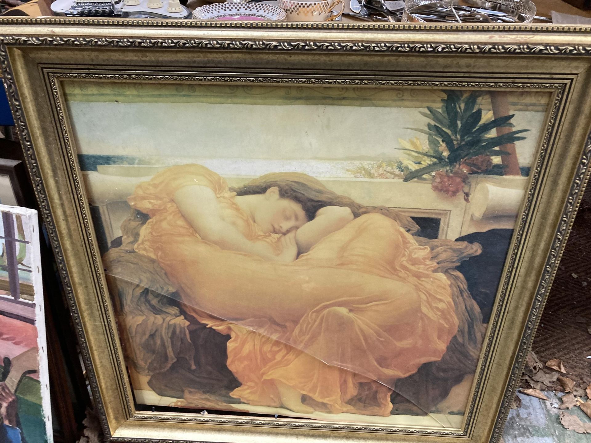 A FRAMED PRINT OF A LADY RELAXING IN AN ORNAGE DRESS (GLASS A/F)