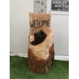 A WOODEN BEAR SCULPTURE WITH WELCOME SIGN IN TREE TRUNK APPROX 80CM IN HEIGHT NO VAT