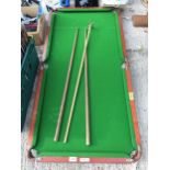 A SMALL TABLE TOP SNOOKER TABLE WITH TWO CUES AND A REST