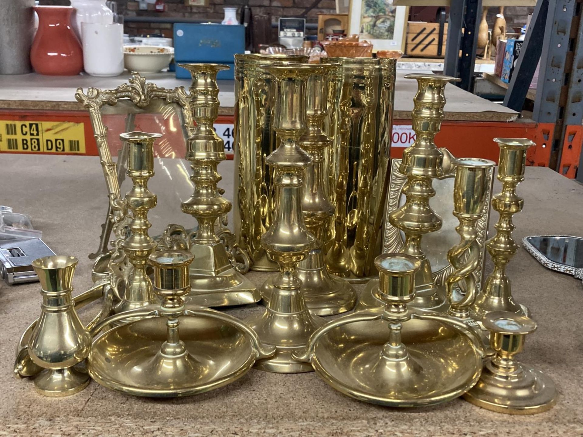 A QUANTITY OF BRASSWARE TO INCLUDE CANDLESTICKS, SHELL CASES, MIRROR, PHOTOGRAPH FRAME ETC