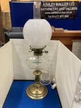 A 19TH CENTURY OIL LAMP CONVERTED TO ELECTRIC WITH A BRASS BASE, CLEAR CUT GLASS RESERVOIR, MILK