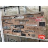 A LARGE WOODEN BOARD CONTAING A LARGE ASSORTMENT OF VINTAGE CAR AND VEHICLE BADGES TO INCLUDE