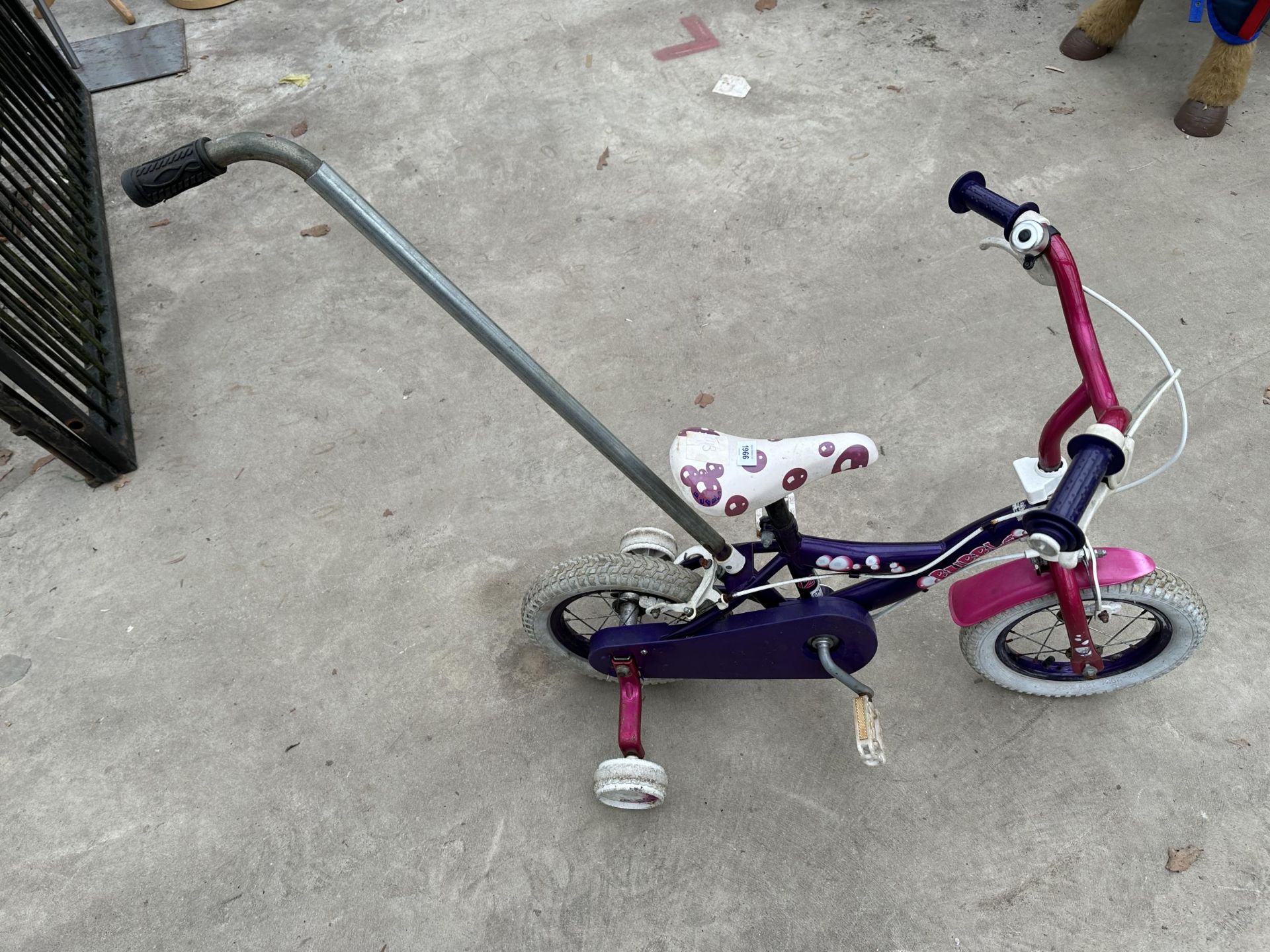 A CHILDS BUBBLE BIKE WITH STABILISERS AND PUSH ALONG POLE