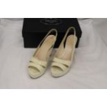 A PAIR OF CREAM HIGH HEELED SHOES, MARKED WITH A GOLD COLOURED 'PRADA' TO THE UNDERSIDE, IN A BOX