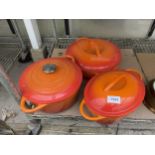 THREE LARGE ORANGE COOKING PANS IN THE STYLE OF LE CREUSET