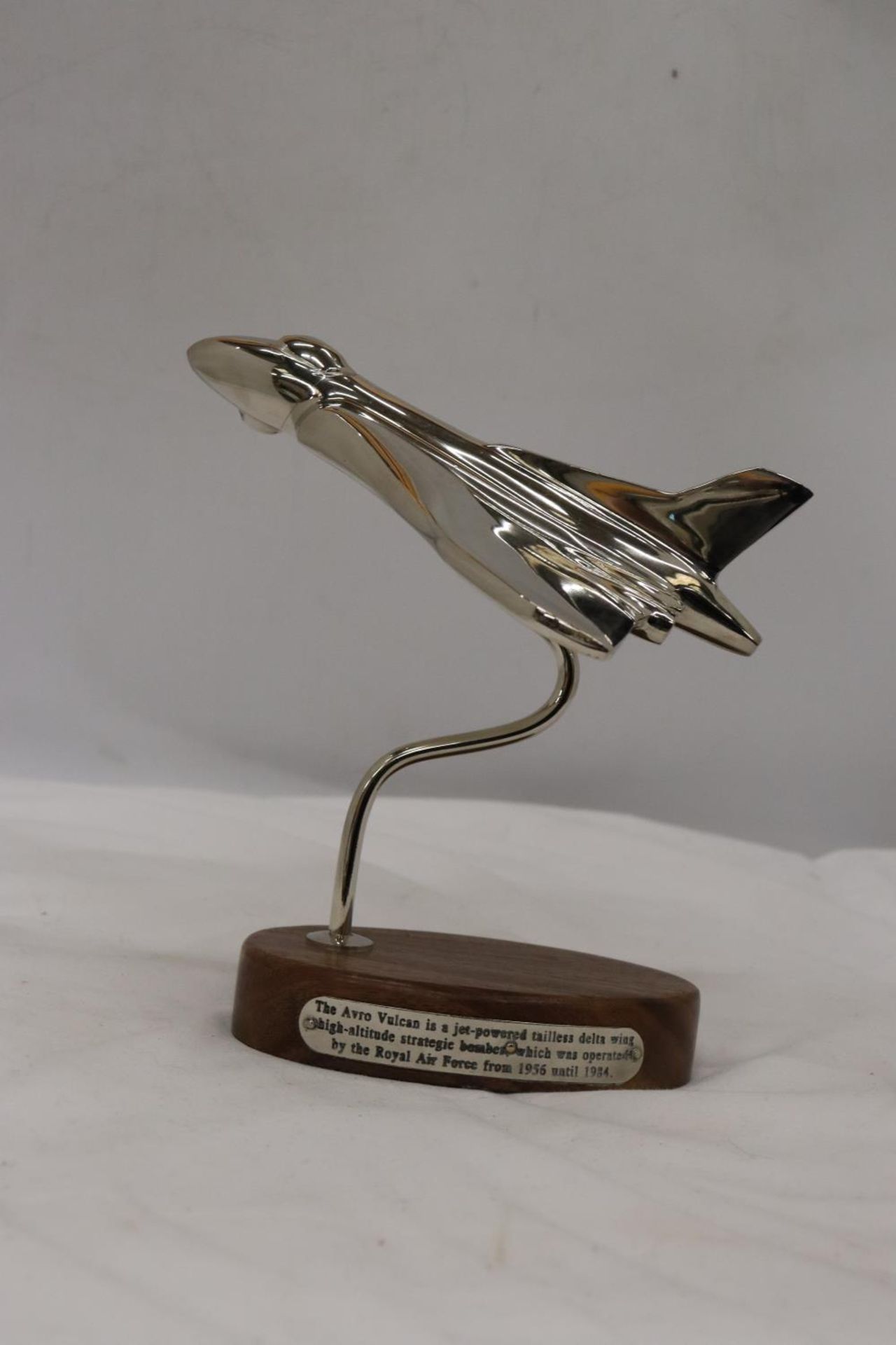 A CHROME MODEL OF AN AVRO VULCAN AEROPLANE ON A HARDWOOD BASE WITH HISTORY PLAQUE, HEIGHT 20 CM