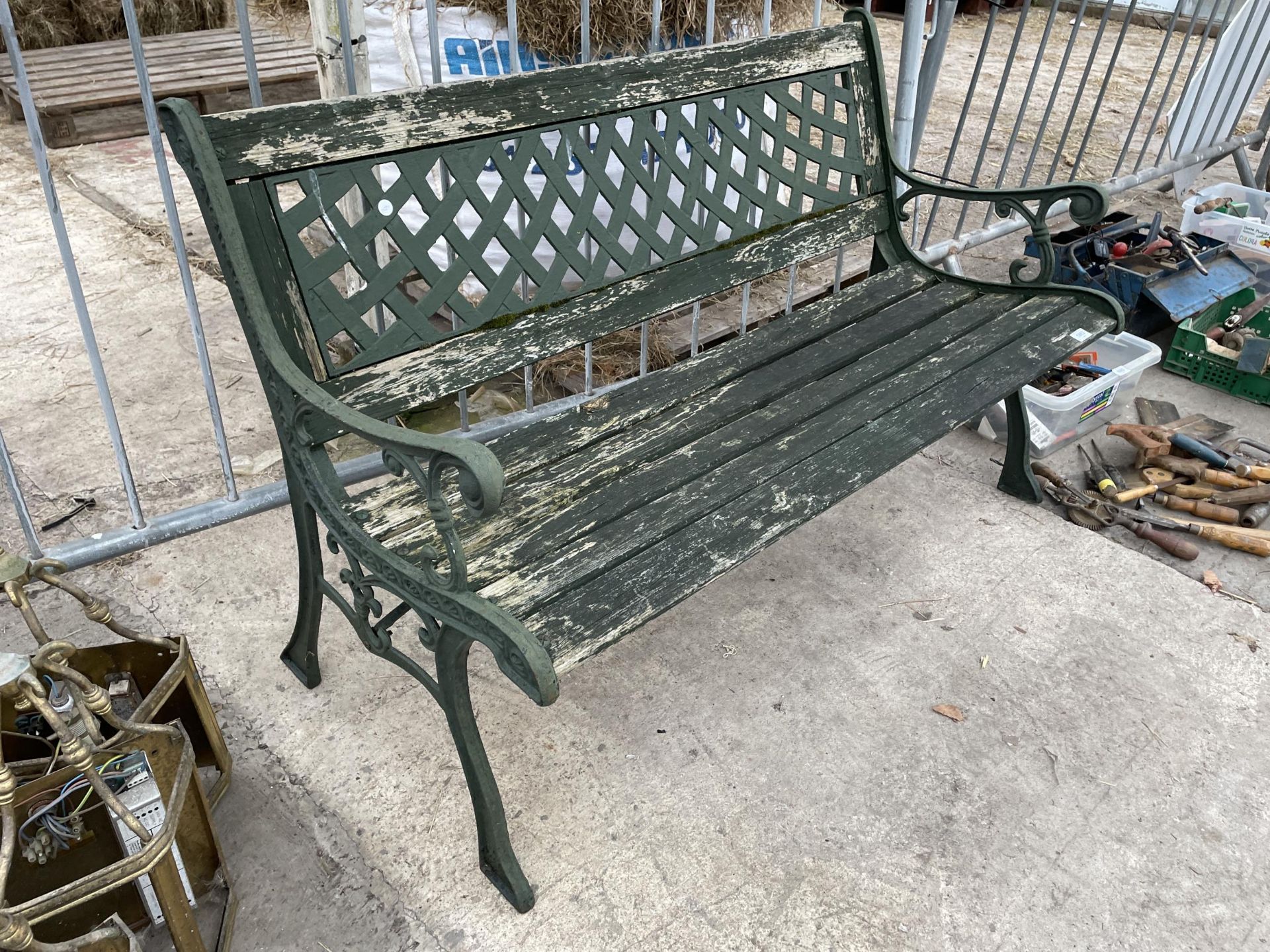 A WOOD SLATTED GARDEN BENCH WITH DECORATIVE CAST ENDS AND BACK