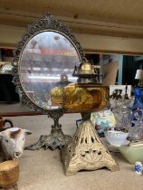 A VINTAGE OIL LAMP WITH AMBER GLASS RESERVOIR AND A DECORATIVE DRESSING TABLE MIRROR