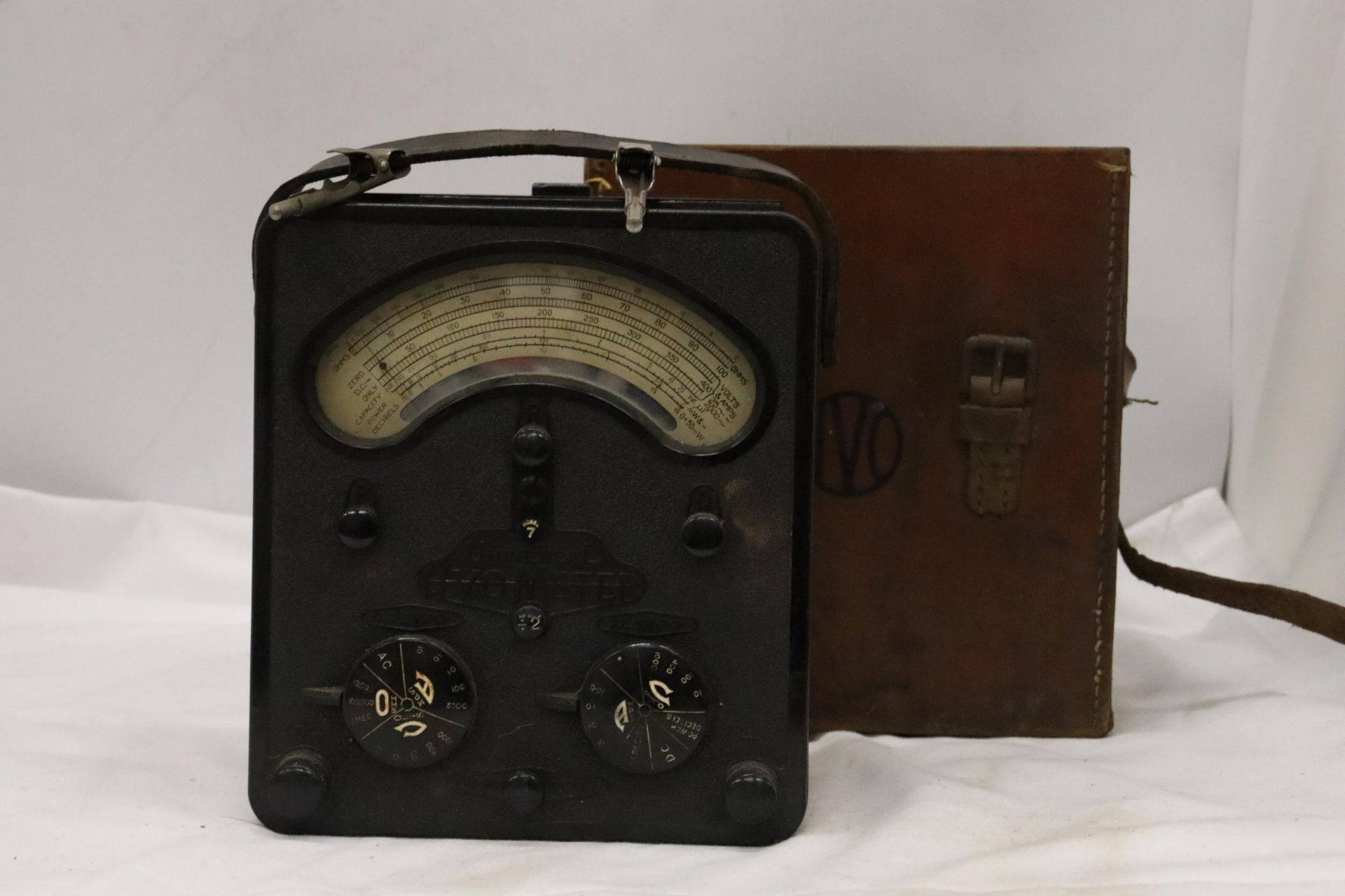 A LARGE BAKELITE AVOMETER IN LEATHER CASE
