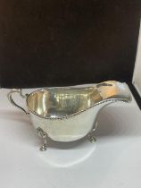 A HALLMARKED BIRMINGHAM SILVER THREE LEGGED SAUCE BOAT