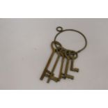 A SET OF LARGE VINTAGE STYLE BRASS KEYS ON A RING HOLDER