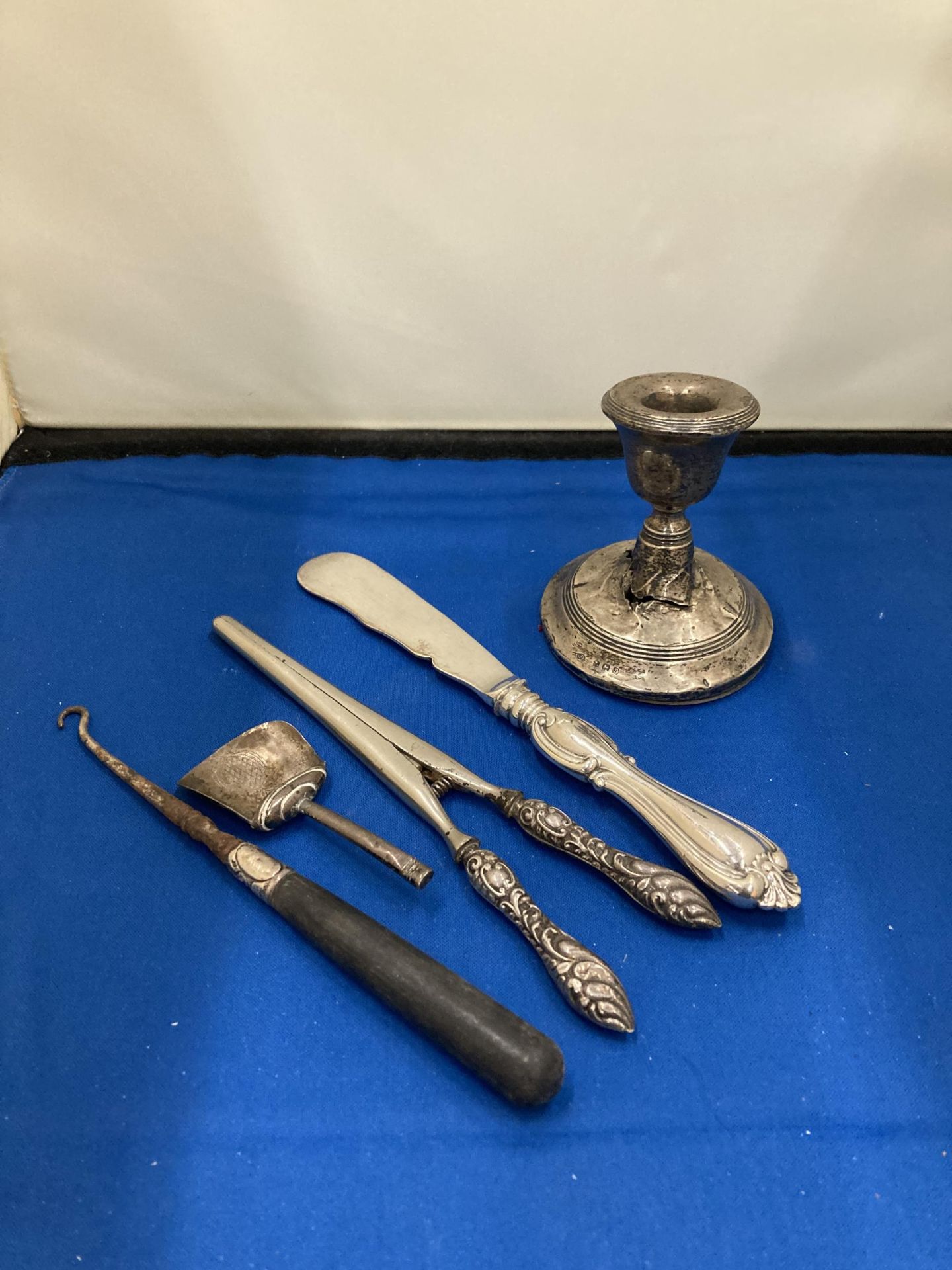 FIVE SILVER ITEMS TO INCLUDE A CANDLE STICK A/F, A SMALL SCOOP, BUTTON HOOK ETC