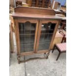 AN EARLY 20TH CENTURY OAK GLAZED AND LEADED TWO DOOR CABINET ON OPEN BASE WITH TURNED BULBOUS