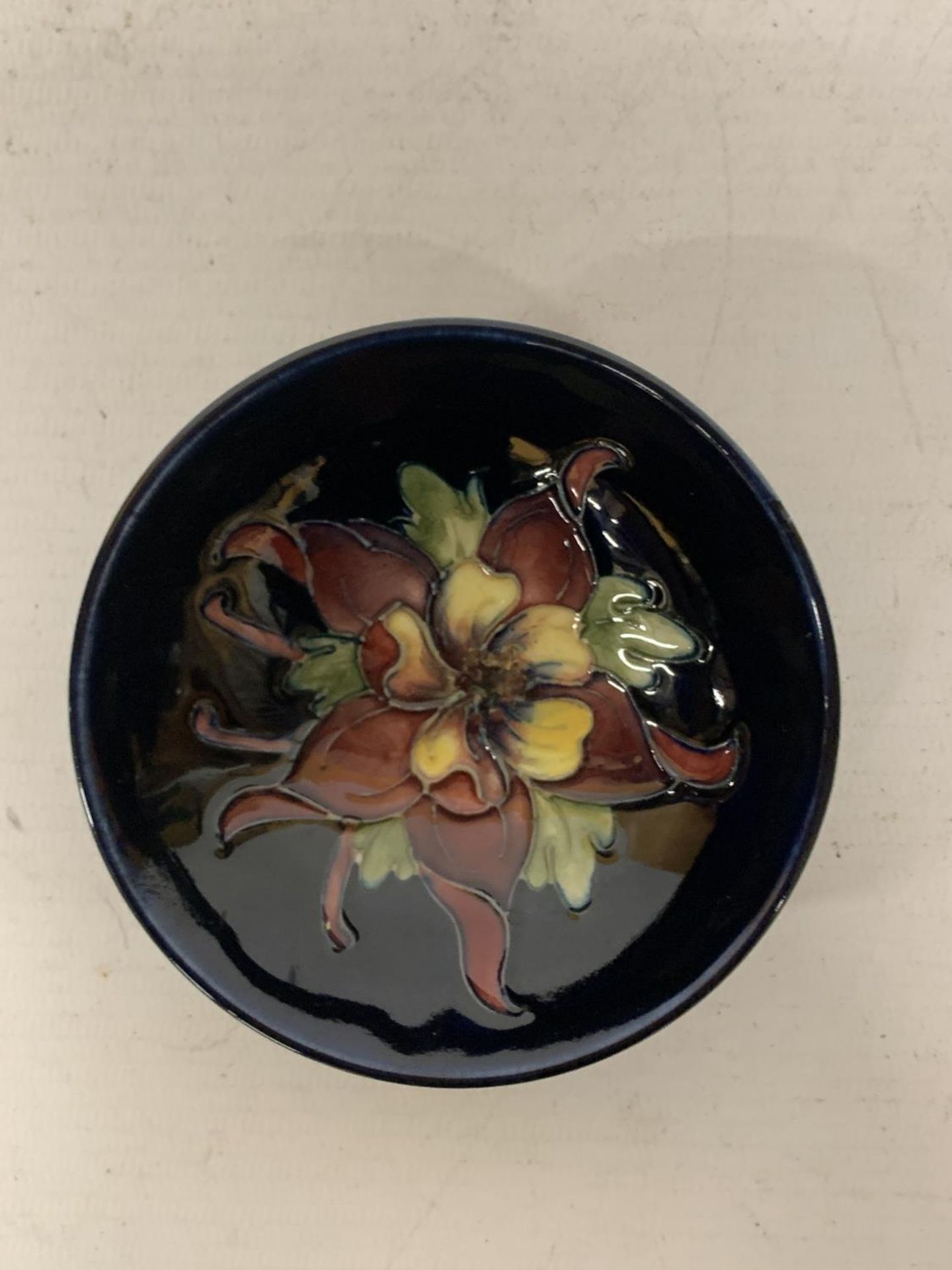 A MOORCROFT COLUMBINE BLUE DISH WITH QUEEN MARY STICKER