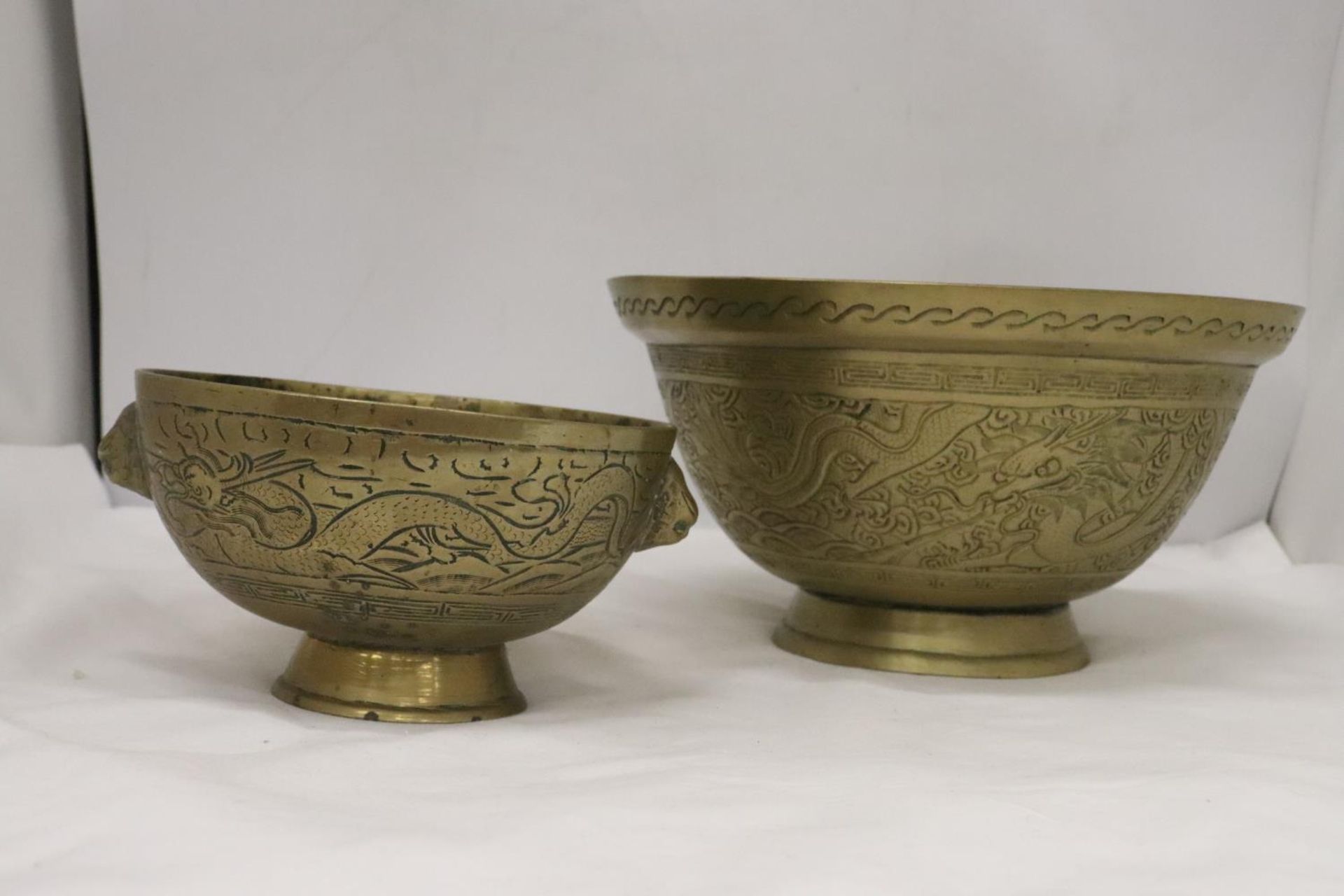 TWO HEAVY BRASS BOWLS WITH ORIENTAL DRAGON DESIGN ONE WITH LION HEAD FEATURES