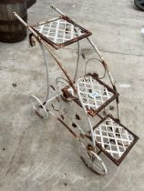 A DECORATIVE METAL THREE TIER PLANT STAND IN THE FORM OF A TROLLEY
