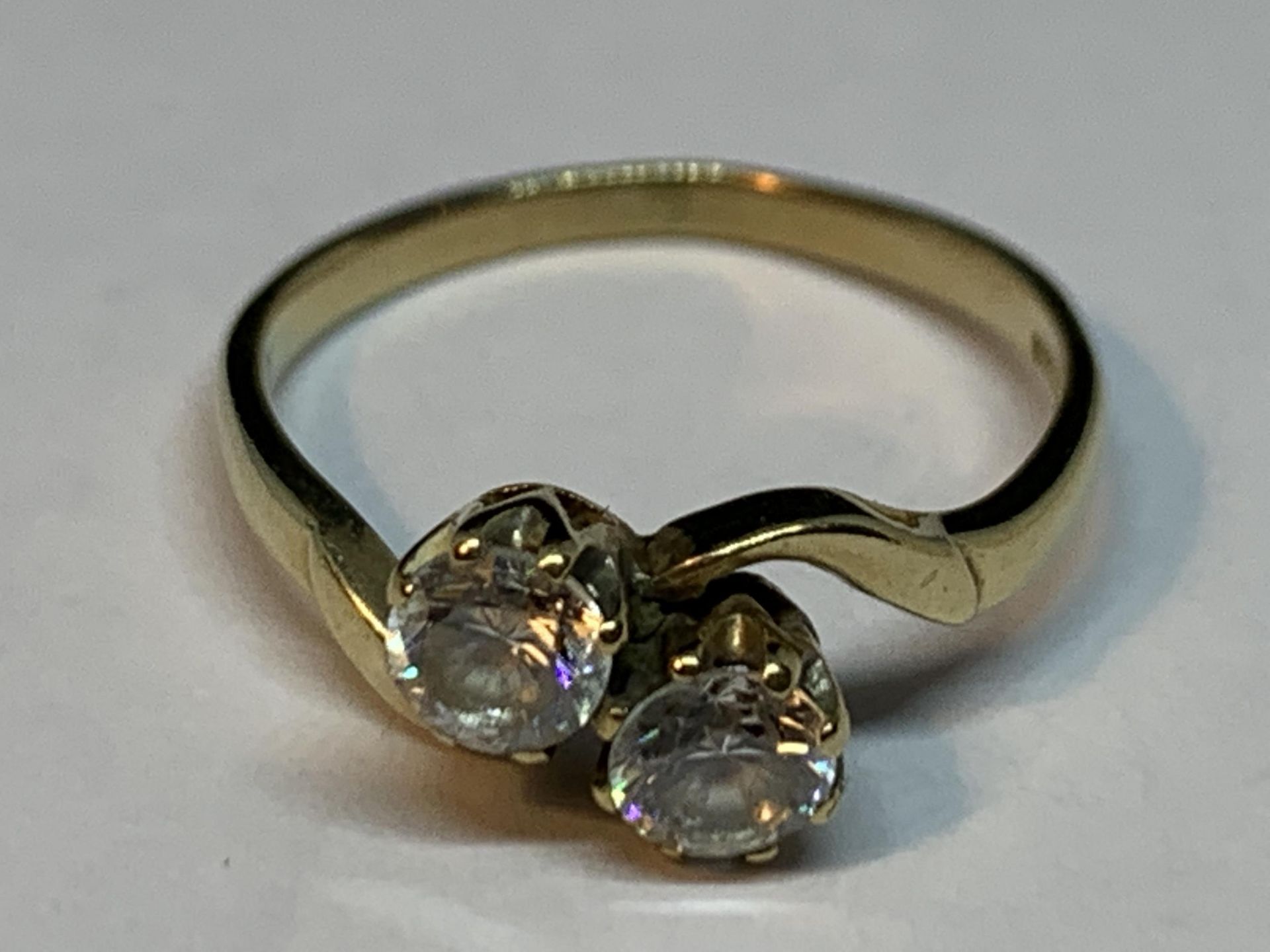 A 9 CARAT GOLD RING WITH TWO CUBIC ZIRCONIA STONES ON A TWIST SIZE K