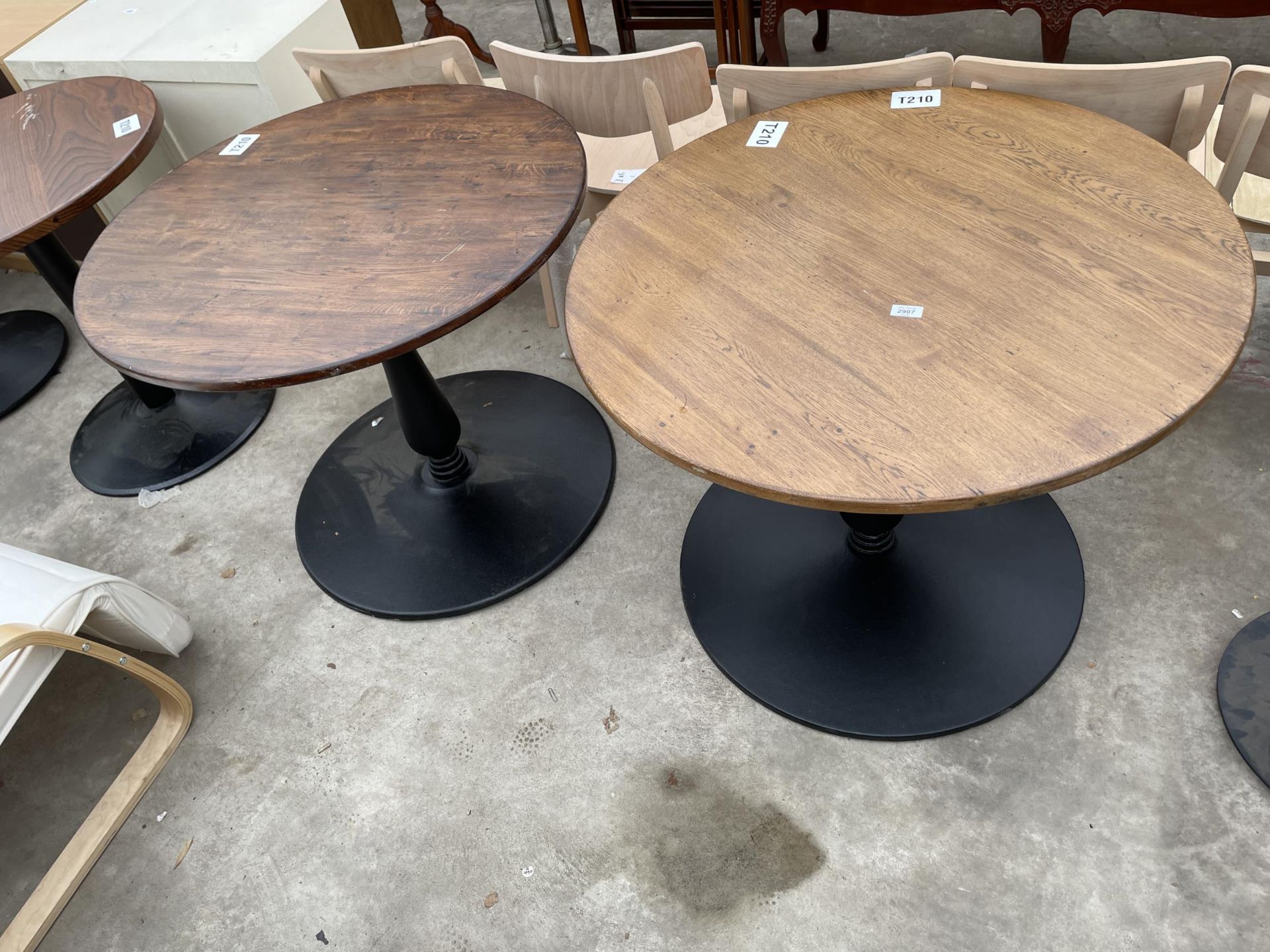 A PAIR OF PUB TABLES ON METALWARE BASES 35" DIAMETER