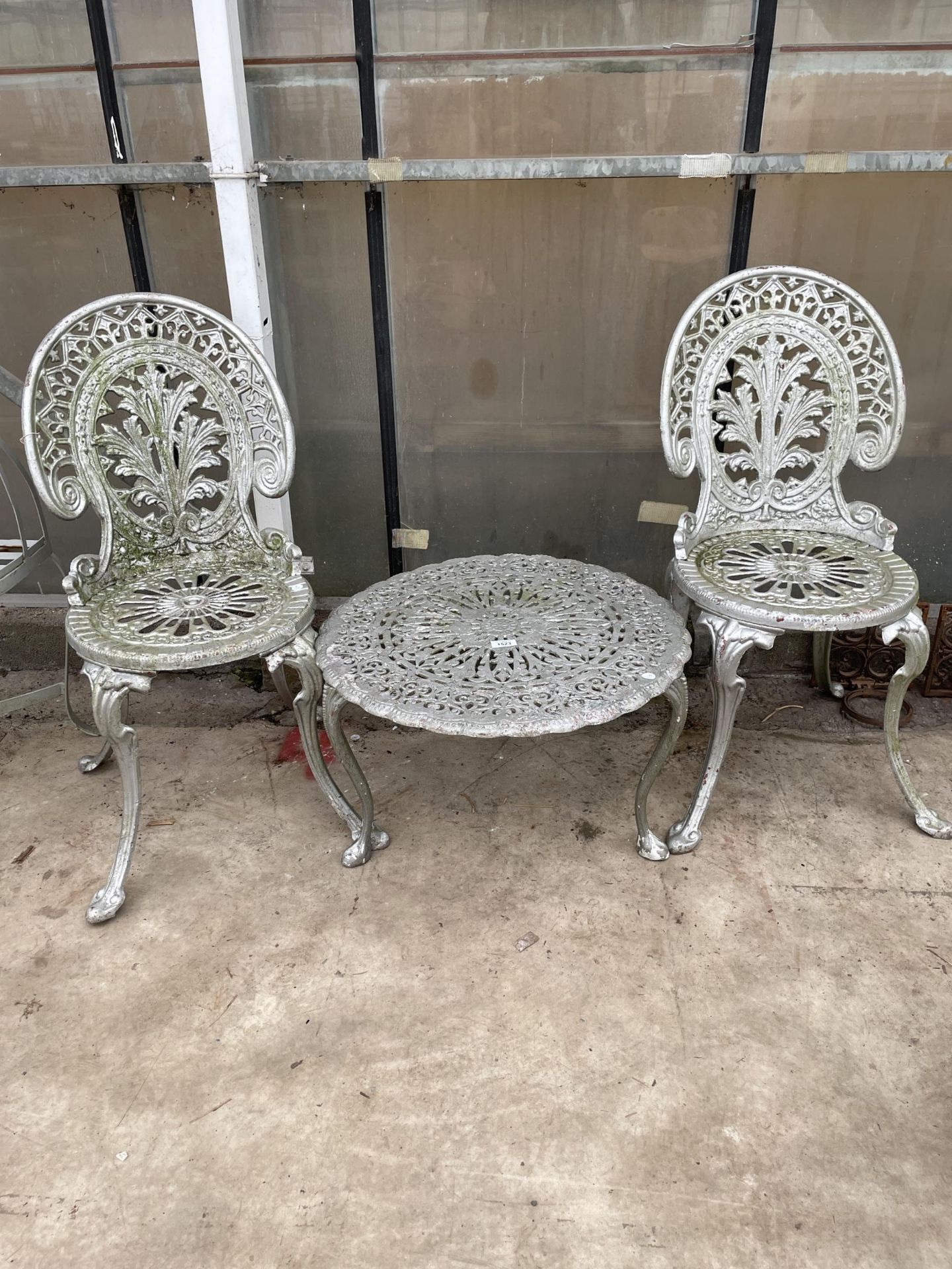 A CAST ALLOY PATIO SET COMPRISING OF TWO CHAIRS AND A ROUND COFFEE TABLE