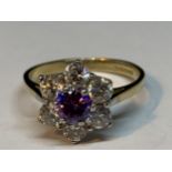 A 9 CARAT GOLD RING WITH CENTRE AMETHYST SURROUNDED BY CUBIC ZIRCONIAS IN A FLOWER DESIGN SIZE P/Q