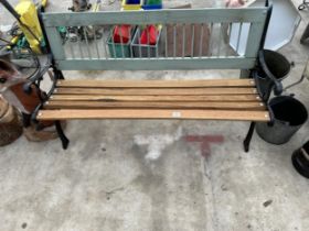 A WOODEN SLATTED GARDEN BENCH WITH DECORATIVE CAST BENCH ENDS