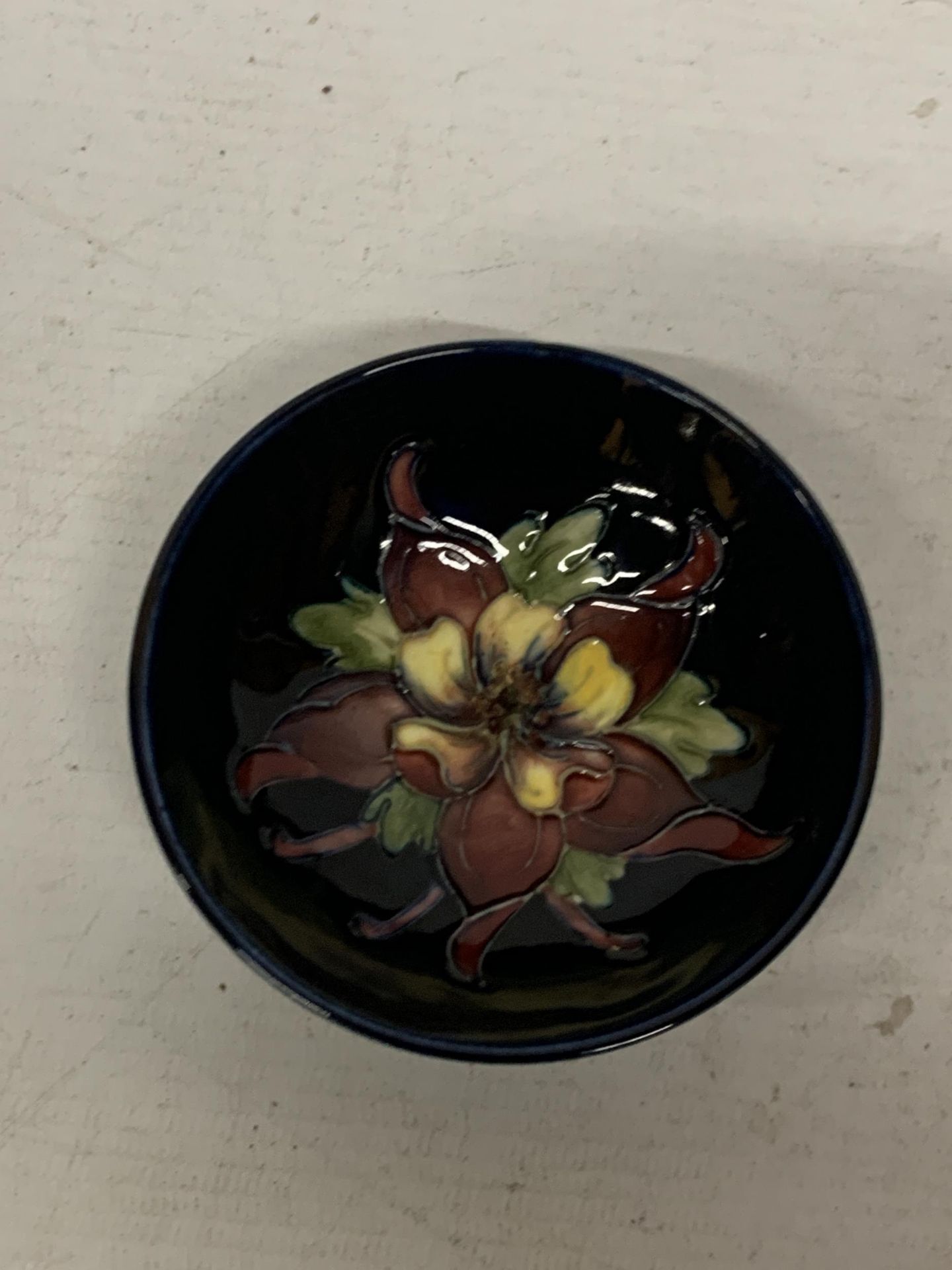 A MOORCROFT COLUMBINE BLUE DISH WITH QUEEN MARY STICKER