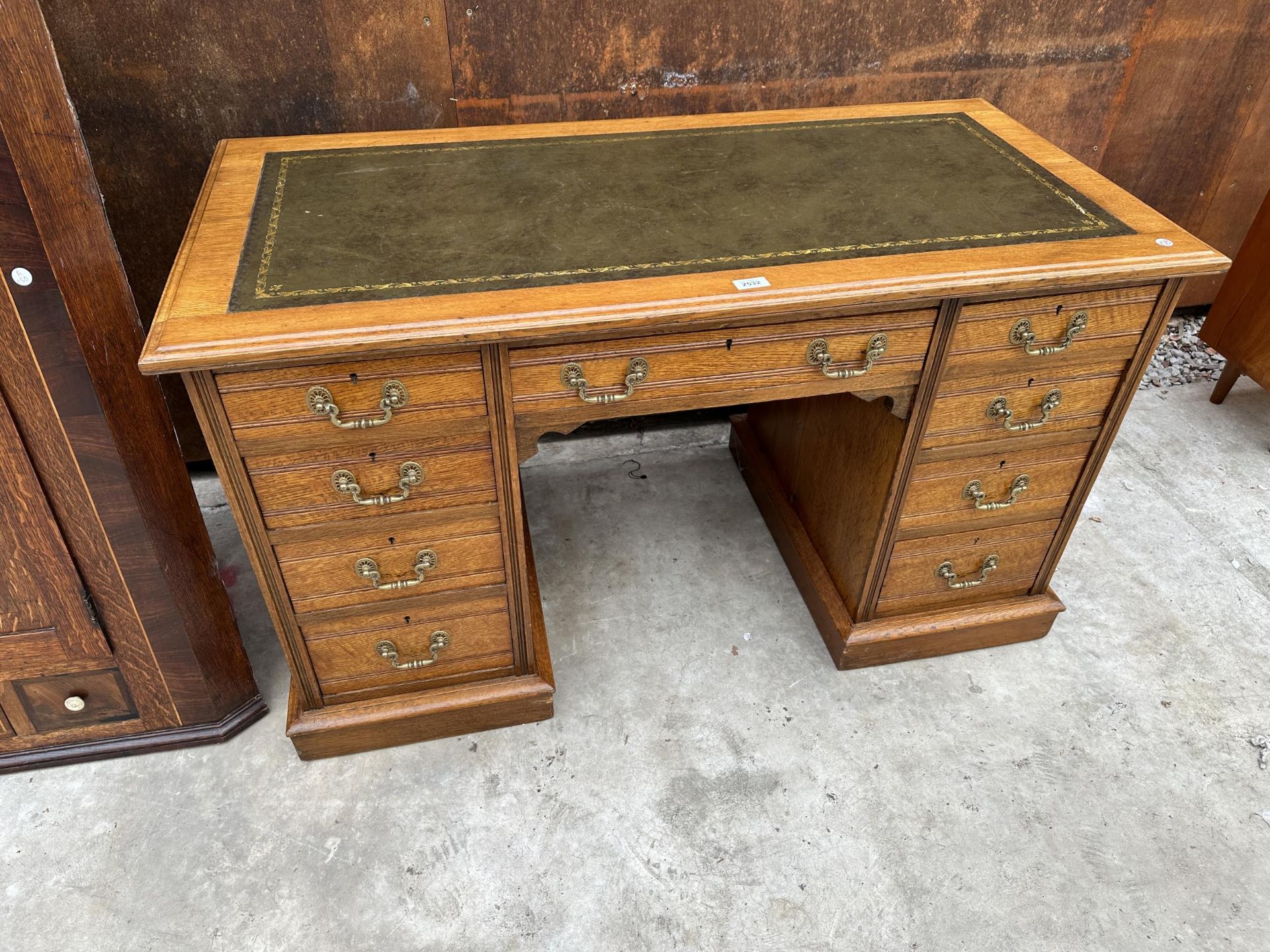 AN EDWARDIAN OAK TWIN PEDESTAL KNEE HOLE DESK ENCLOSING NINE DRAWERS WITH INSET LEATHER TOP 48" X