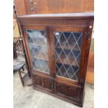 AN OAK JAYCEE GLAZED AND LEADED TWO DOOR CUPBOARD WITH LINEN FOLD DOORS TO BASE 38" WIDE