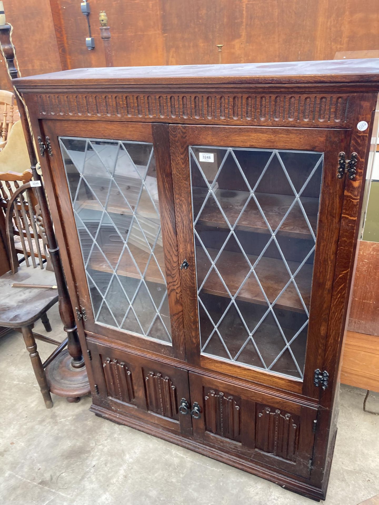 AN OAK JAYCEE GLAZED AND LEADED TWO DOOR CUPBOARD WITH LINEN FOLD DOORS TO BASE 38" WIDE