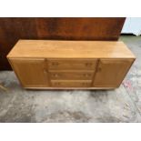 AN ERCOL LIGHT ELM SIDEBOARD WITH TWO DOORS AND THREE DRAWERS, THE TOP DRAWER HAVING REMOVABLE