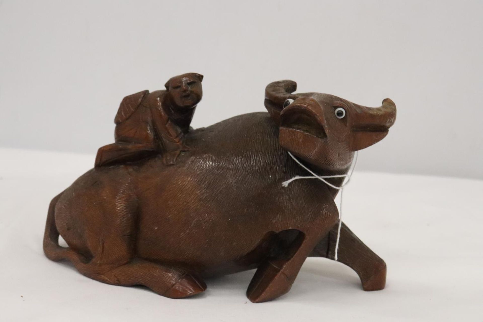 AN ORIENTAL WOODEN CARVED WATER BUFFALO WITH CHILD RIDER, A/F TO LEG, HEIGHT 12CM, LENGTH 22CM