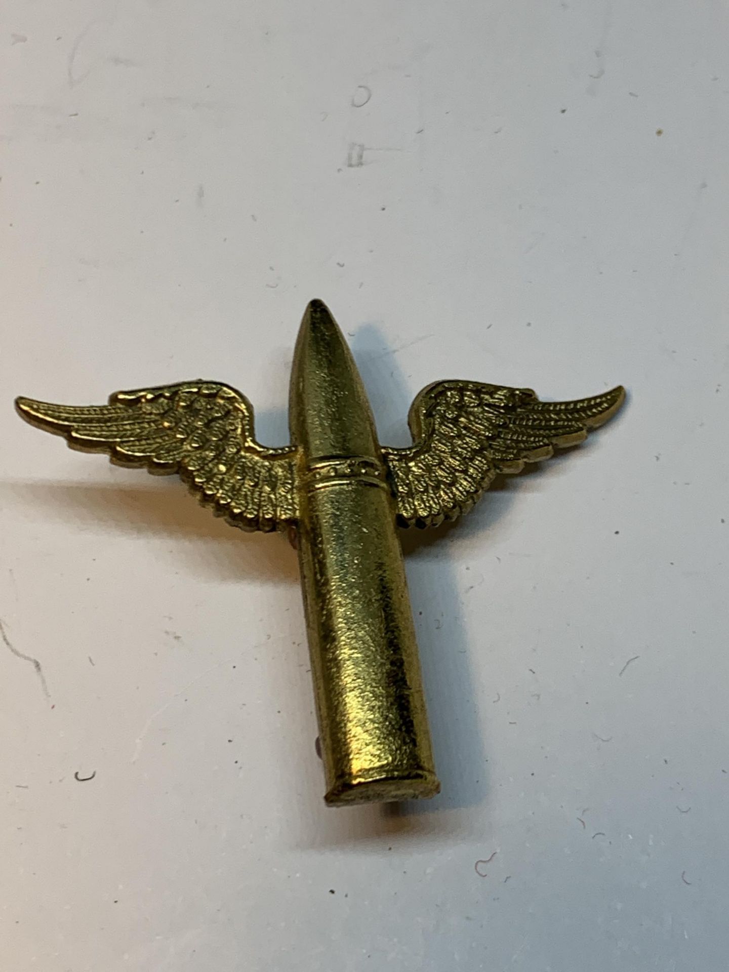 A BRASS ROYAL AIR FORCE AIR GUNNER BADGE WITH BULLET AND WING DESIGN