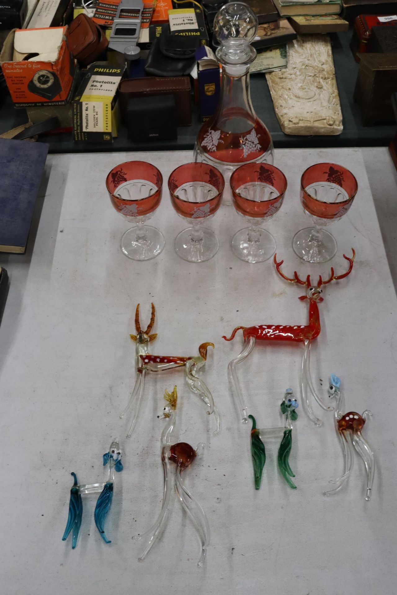AN ETCHED CRANBERRY AND CLEAR GLASS DECANTER AND FOUR WINE GLASSES PLUS A QUANTITY OF GLASS ANIMALS